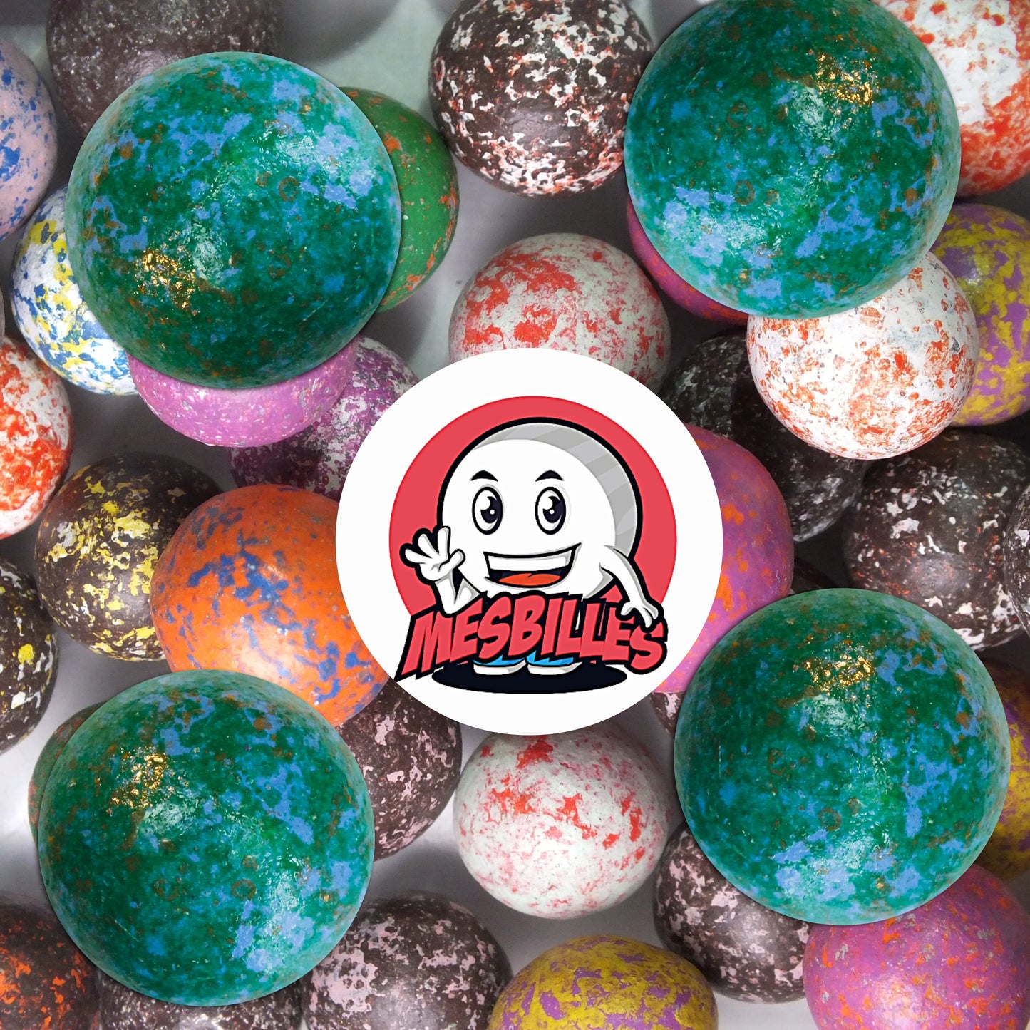 Collection de billes en terre multicolores avec plusieurs billes vert moucheté de 25 mm au premier plan, ambiance rétro et ludique