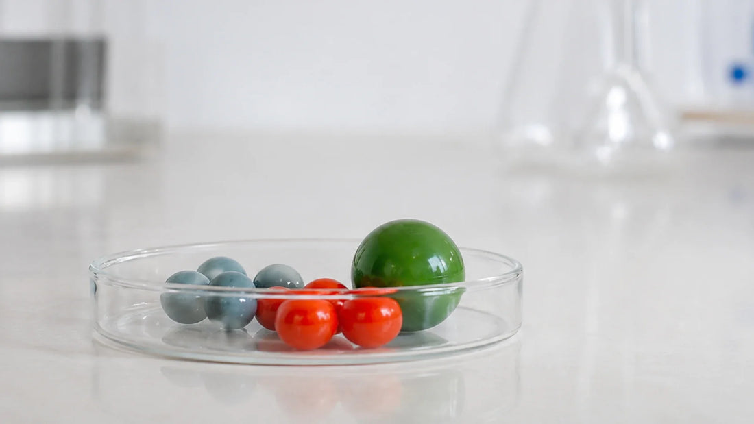 Une poignée de billes de verre dans un petit bocal transparent, posé sur un plan de travail clair.