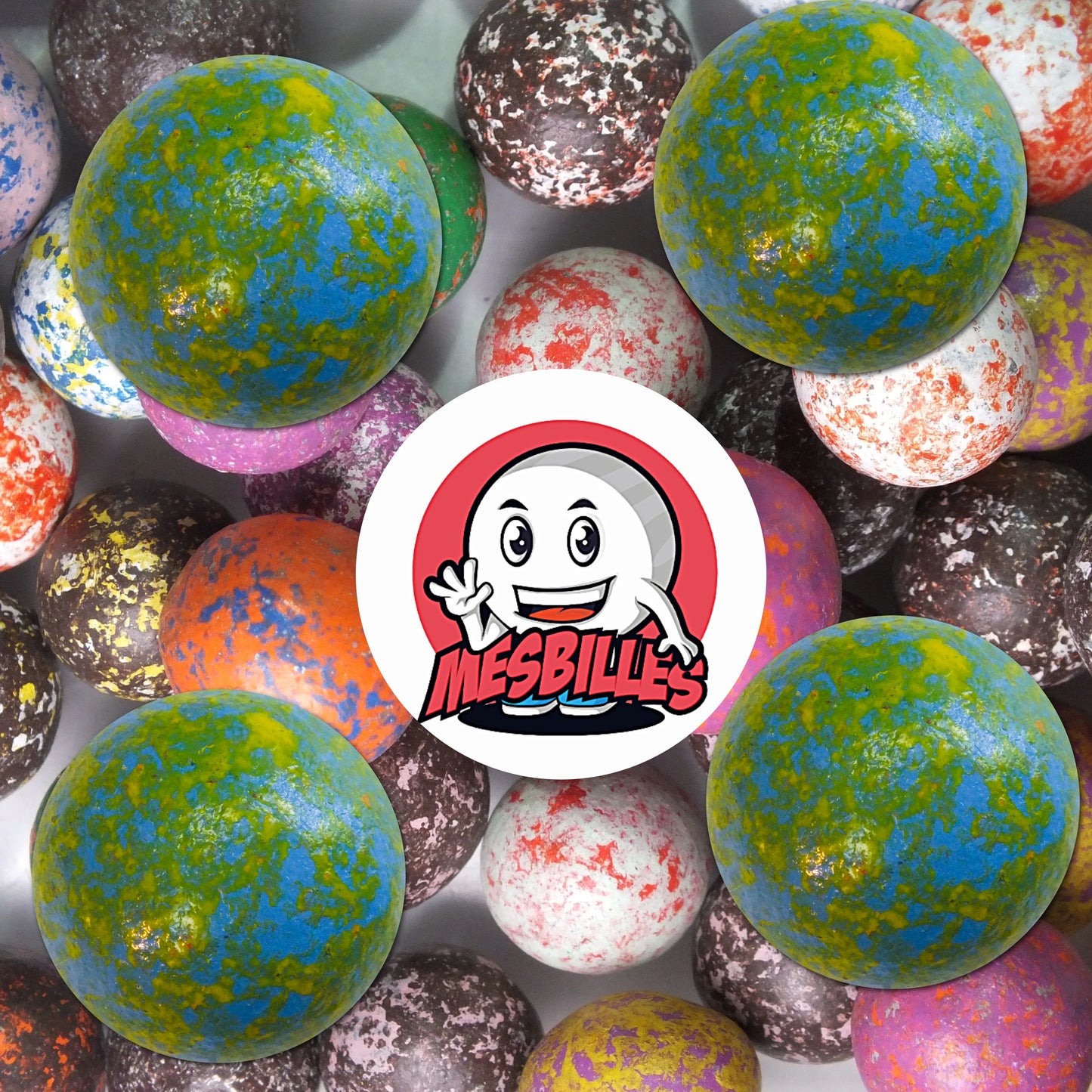 Collection de billes en terre multicolores avec plusieurs billes bleu moucheté de 25 mm au premier plan, ambiance rétro et ludique