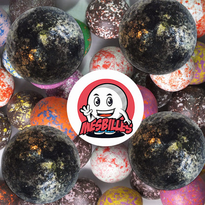 Collection de billes en terre multicolores avec plusieurs billes noir moucheté 25 mm en premier plan, ambiance rétro et élégante