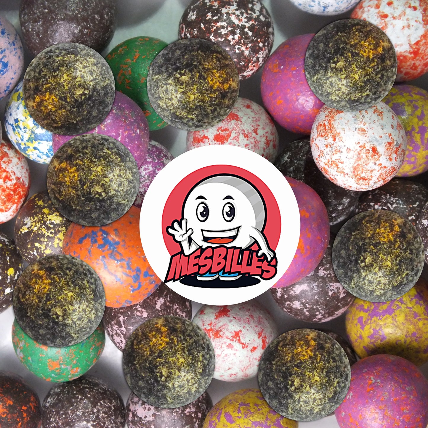 Collection de billes en terre multicolores avec plusieurs billes noir mouchetée 10 mm au premier plan, ambiance rétro et ludique