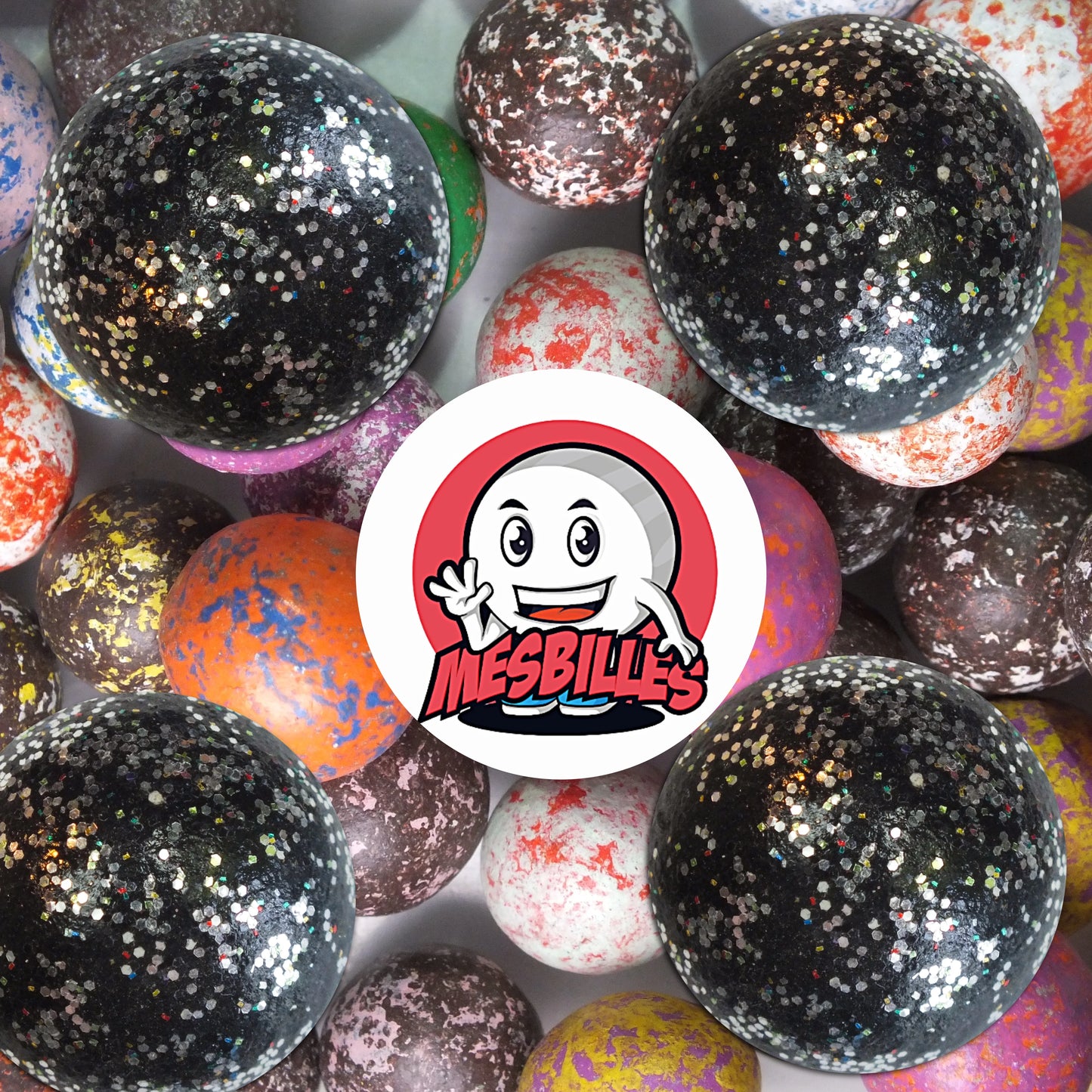 Collection de billes en terre multicolores avec plusieurs billes noir paillettes 25 mm au premier plan, ambiance élégante et festive